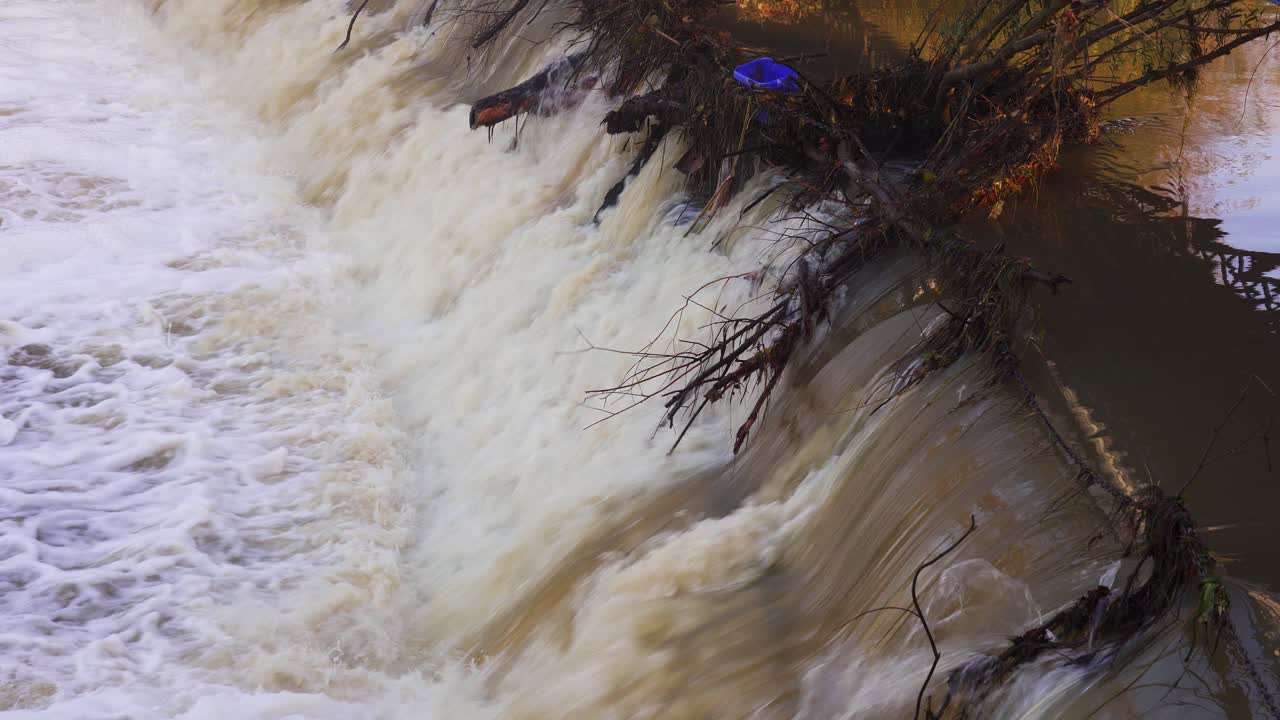 Debris caught on the cascade during high water levels close to flooding the river Leam in Leamington Spa, England