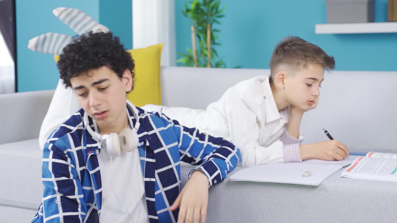 공부하는 동안 지루한 동생을 위로하는 소년.