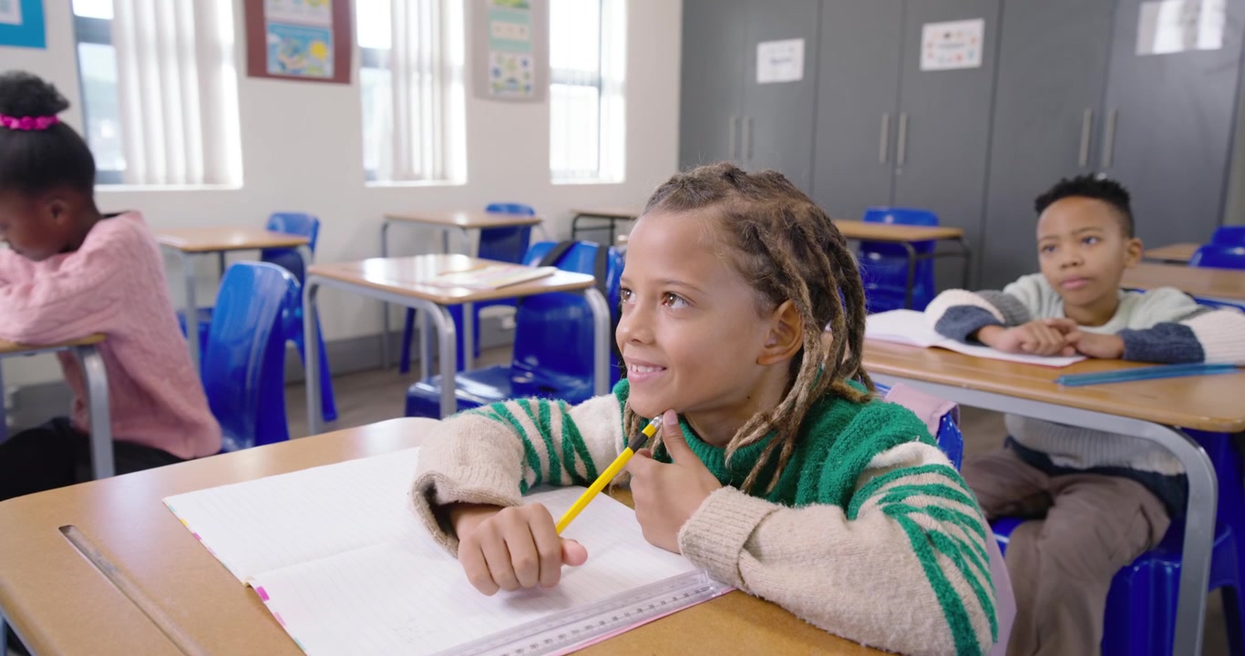 Studenti afroamericani che scrivono in classe, con lo studente al centro che fa una pausa con una matita gialla e un quaderno