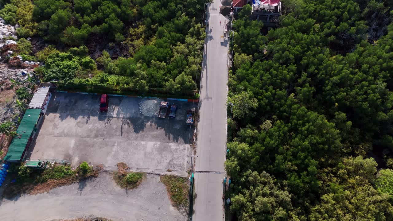 Authentic top-down 4K aerial view of a small housing community with corrugated rooftops and narrow streets, contrasting with tropical greenery in the Philippines