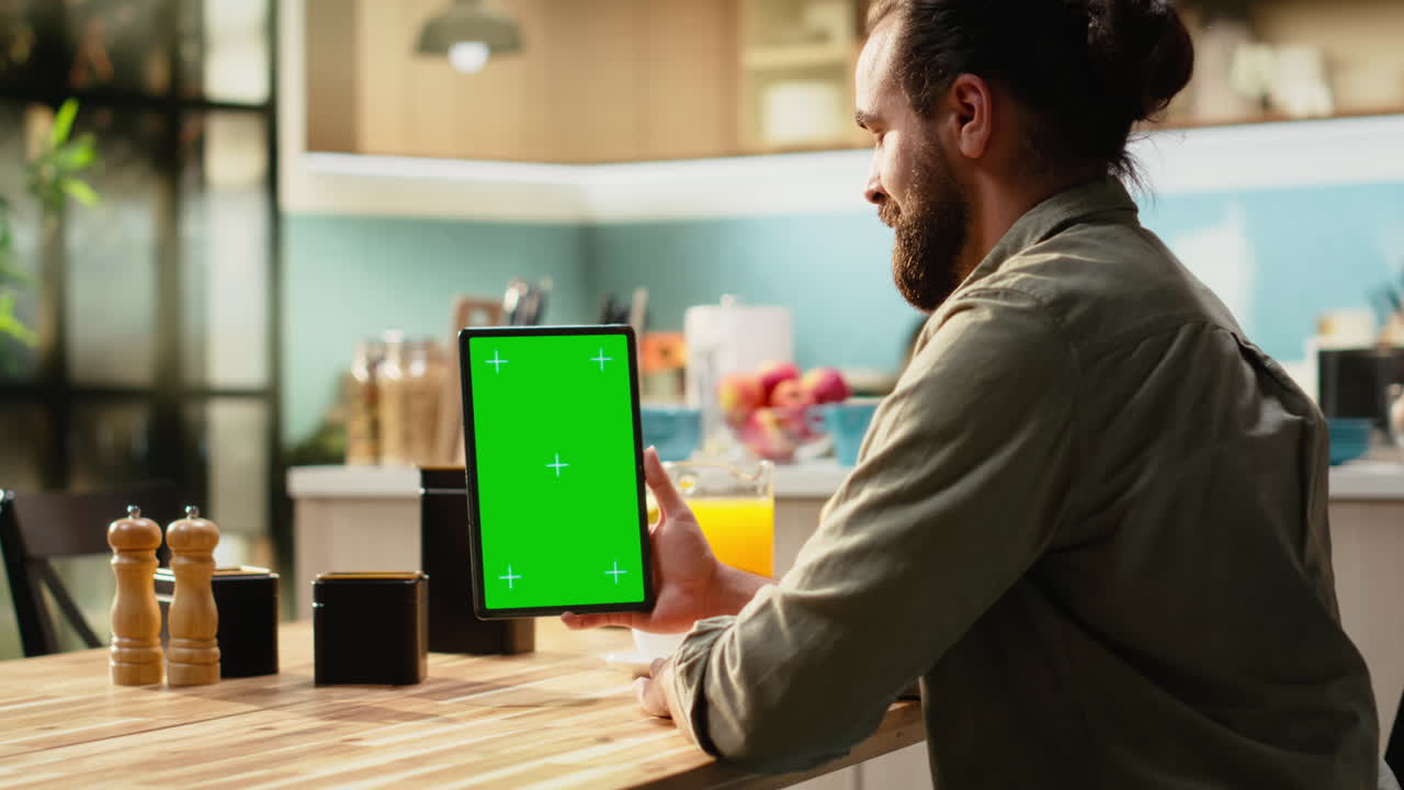 Schermo verde verticale su tablet con adulto che lavora da remoto a casa
