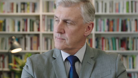 portrait-of-pensive-caucasian-businessman-boss-turns-head-looking-serious-at-camera-in-library-office-study-wearing-suit