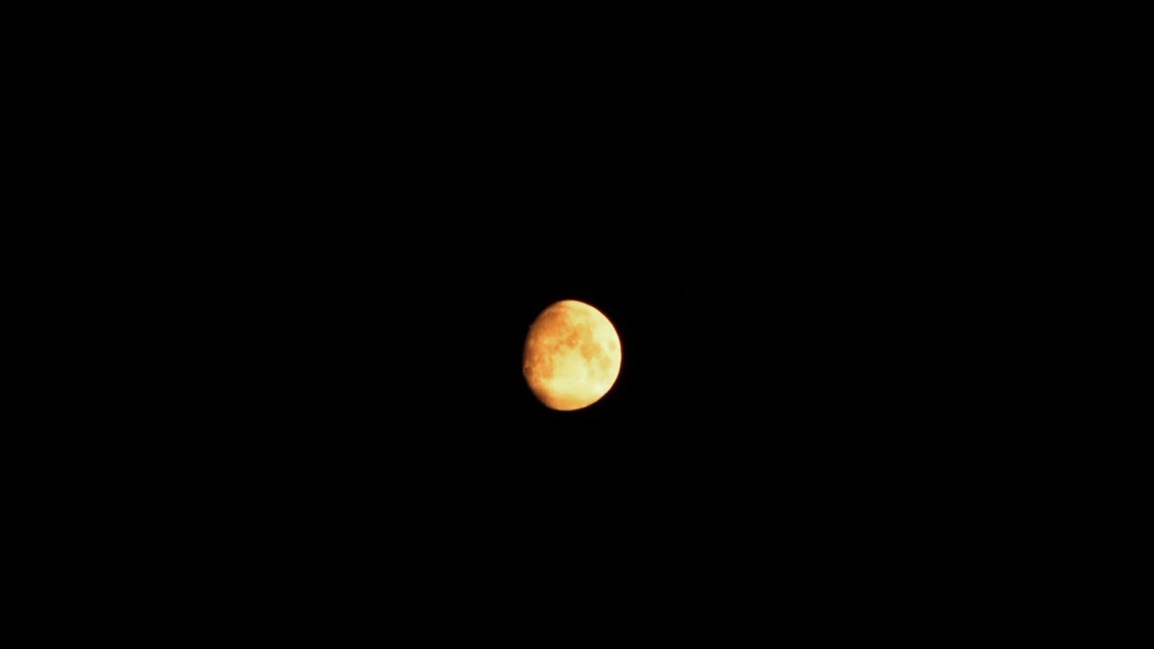 Glowing moon covered with dramatic clouds in slow motion (from all covered by clouds to fully visible)