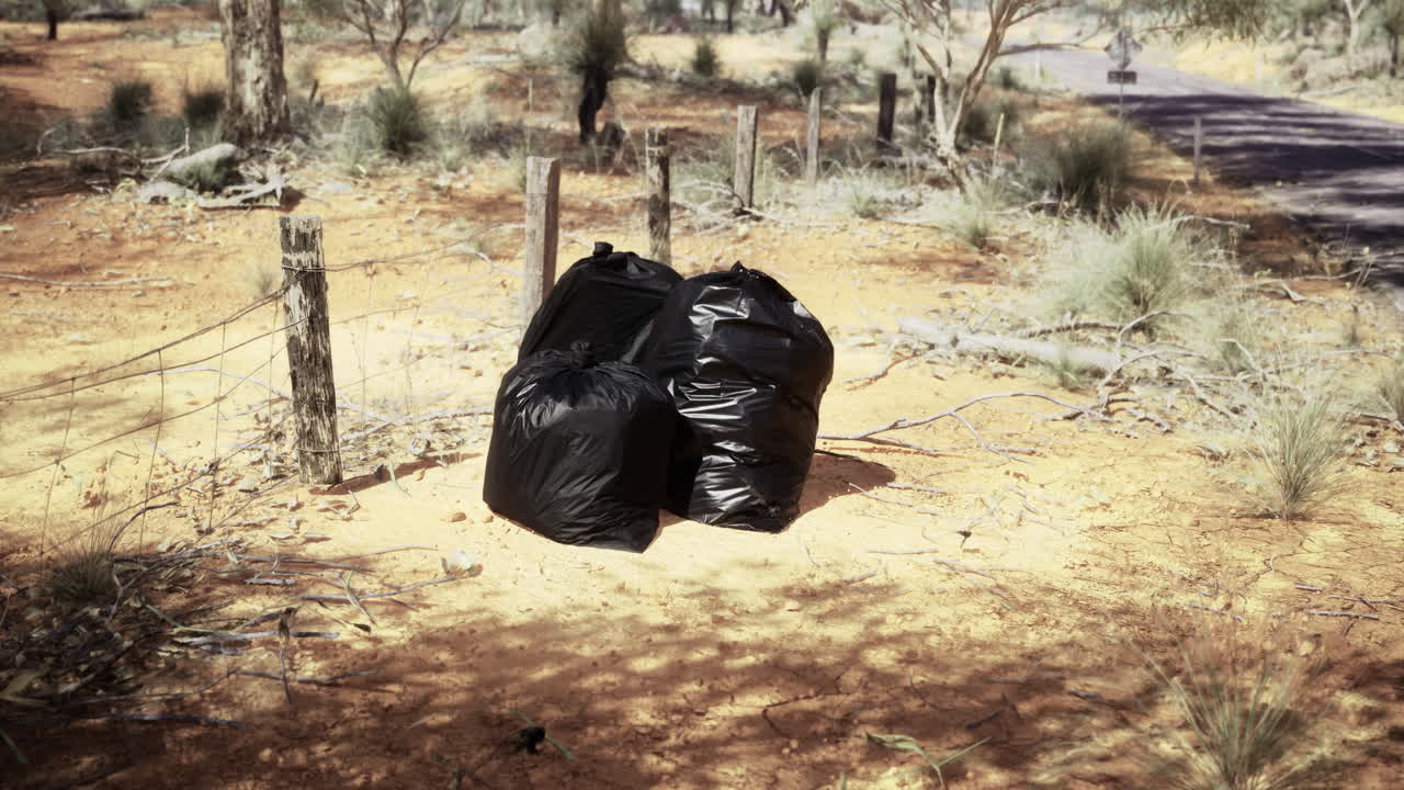 Waste disposal in a natural area with trees and dirt road nearby