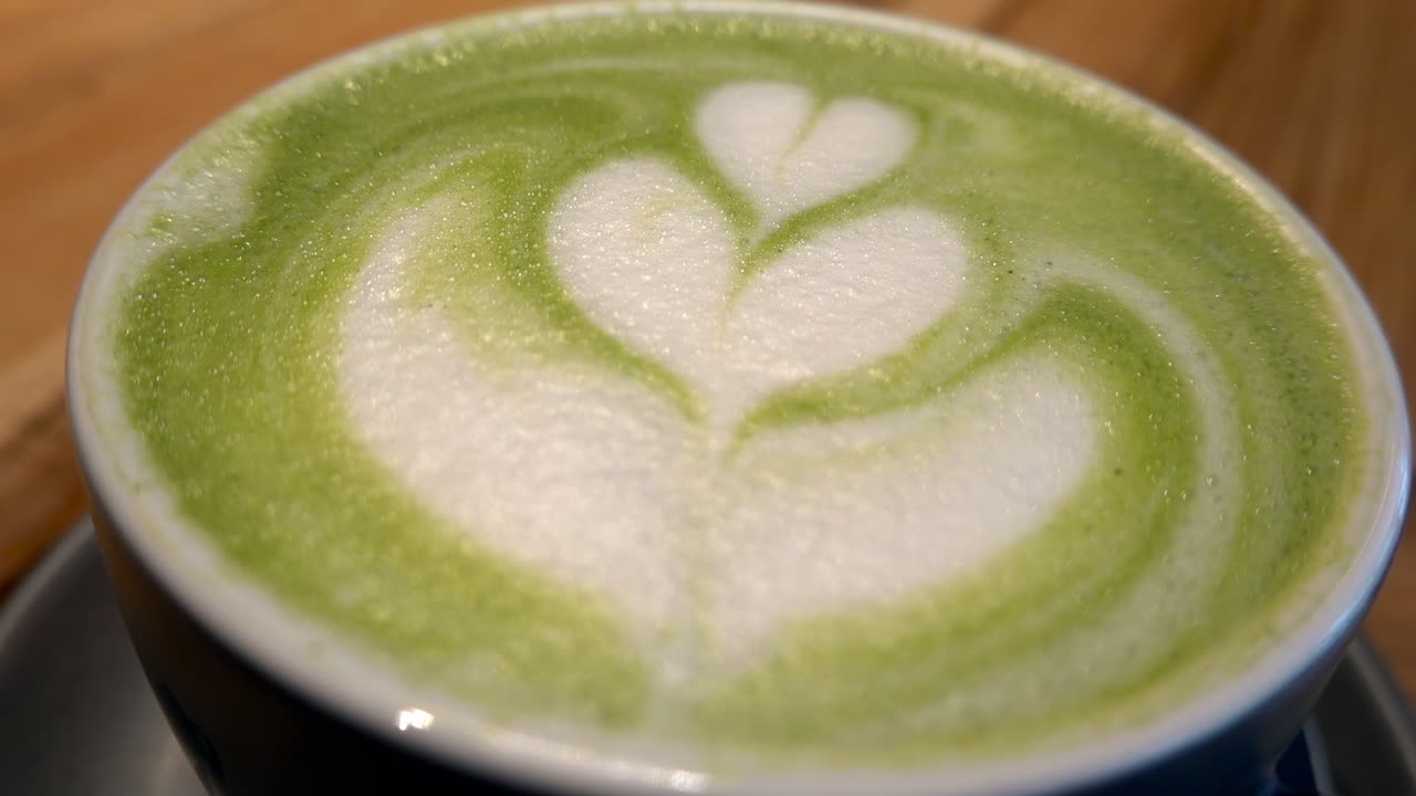 Close up of a a cup of matcha latte on a table at a cafe