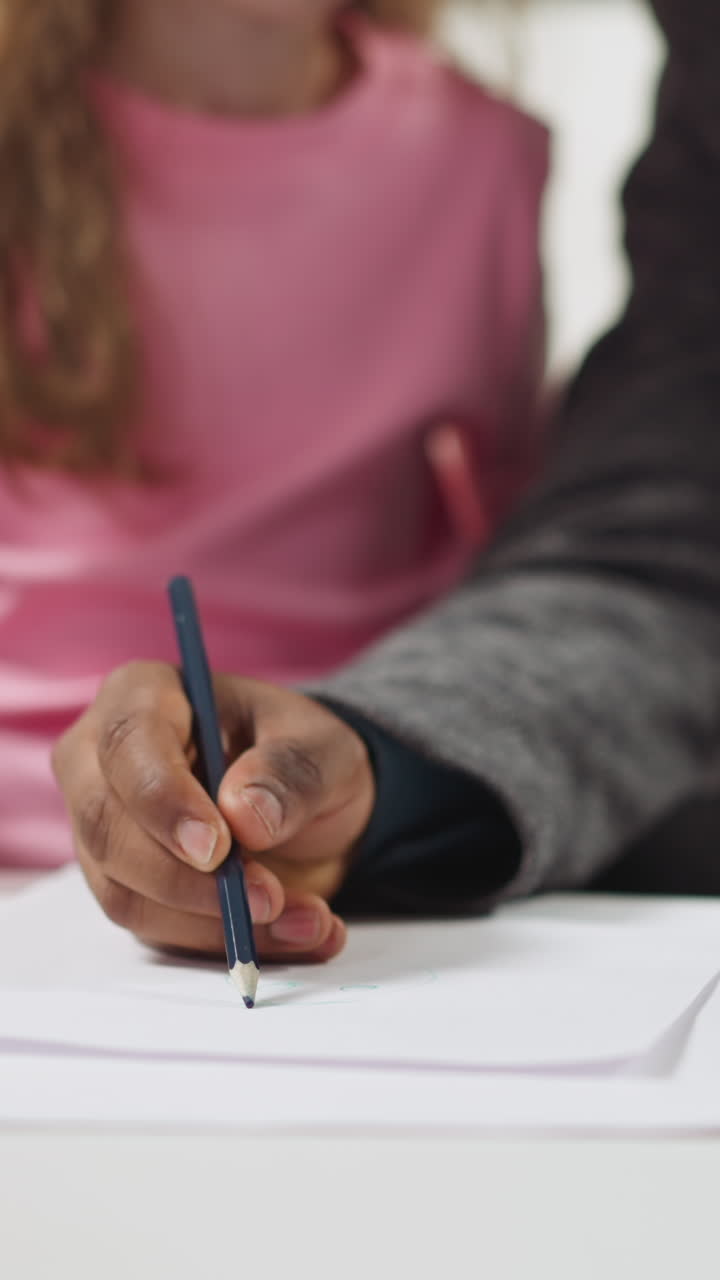 African-American man draws picture on paper sheet teaching little girl English language at private lesson in living room closeup slow motion