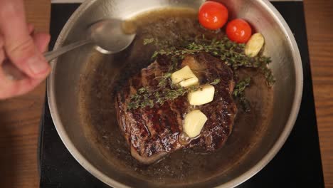 cocinando un filete en una sartén con mantequilla, ajo y tomillo