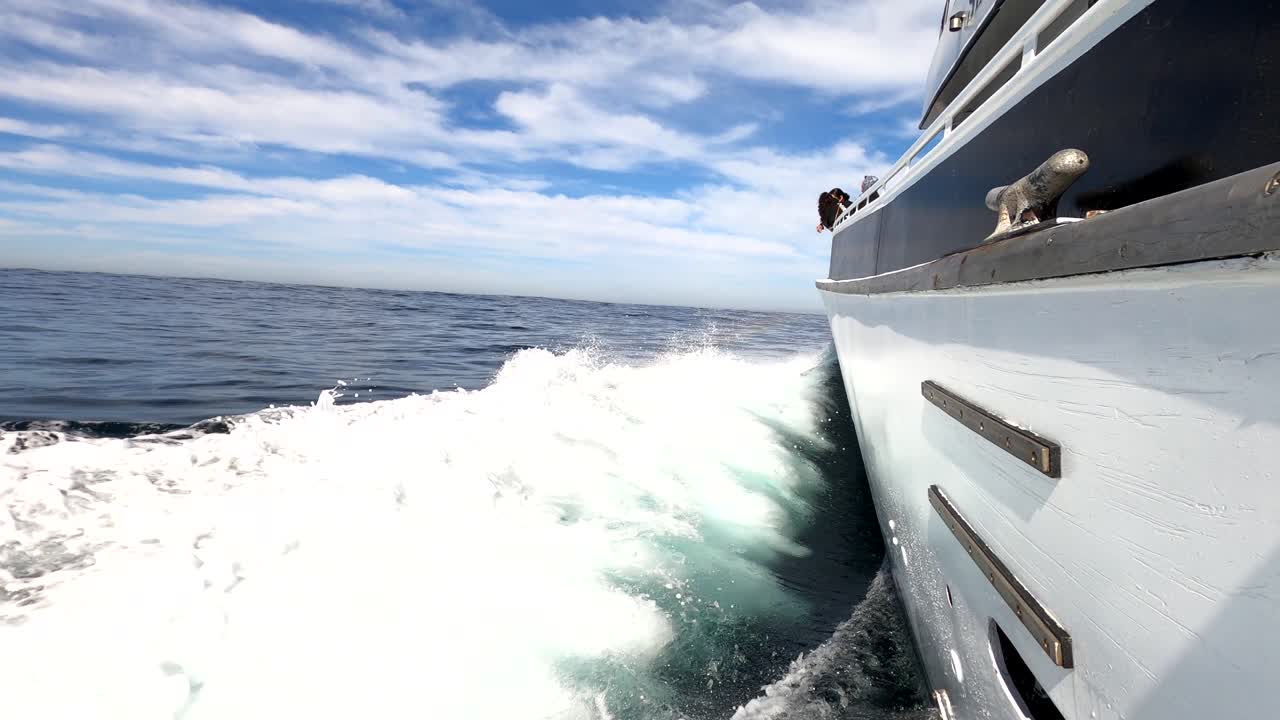 Sideboard view of luxury yacht sailing through ocean water making foamy trail