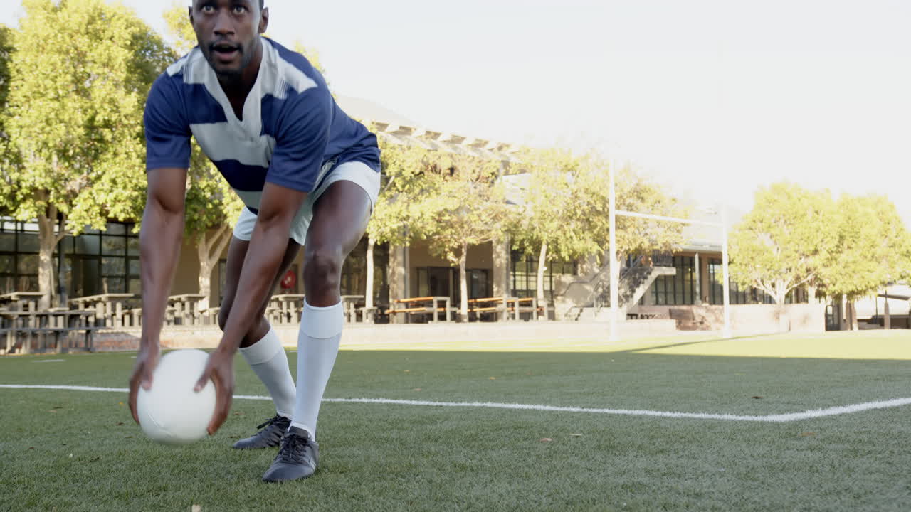 Playing rugby, african american male athlete in uniform holding ball on field, preparing, copy space