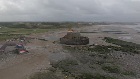 Drone flying away from a historical fort revealing the coastal village Ambleteuse in France