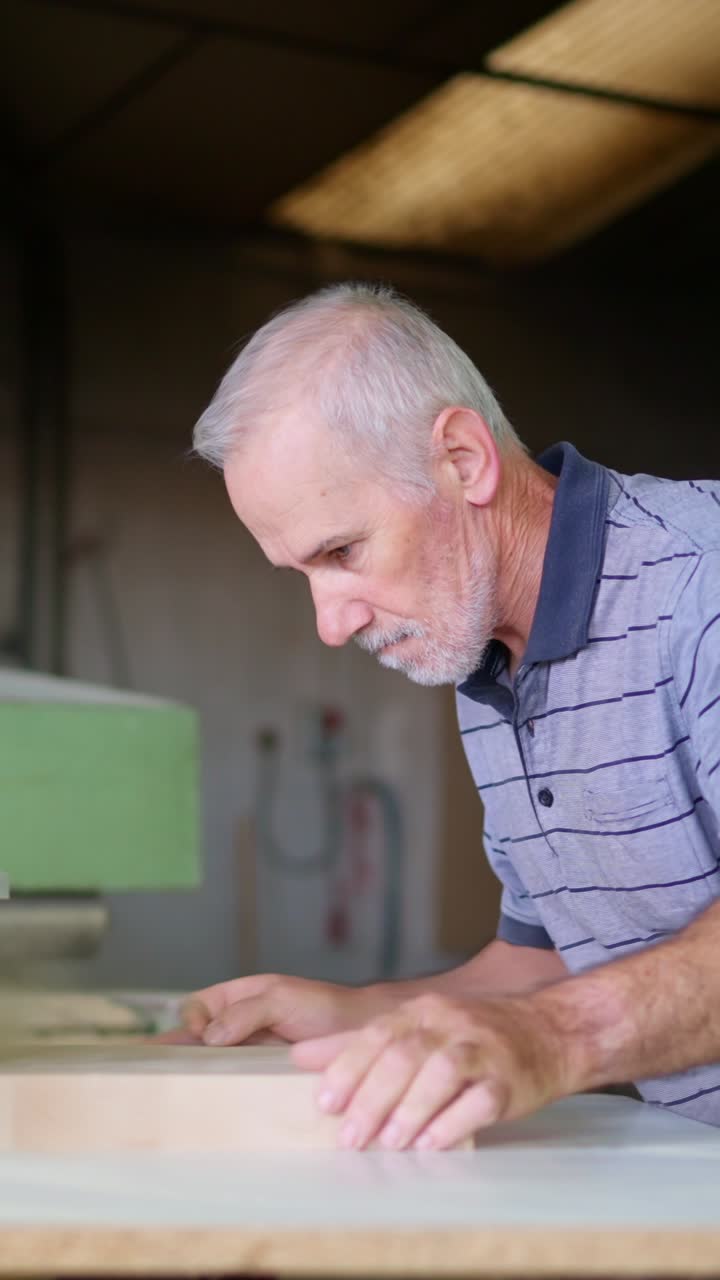 Senior Man Sanding Wood with a Belt Sander in Workshop