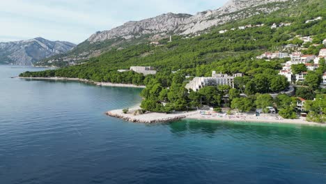 slow drone panning shot brela beach croatia shady pine forest in background