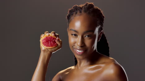 woman smiling holding a grapefruit