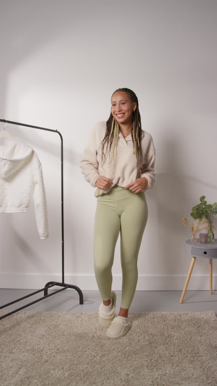 vídeo vertical de pov de una influyente femenina de las redes sociales produciendo contenido generado por el usuario en el estudio modelando una variedad de trajes de moda filmados en tiempo real 8