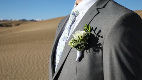 groom wearing boutonniere on grey suit with floral tie