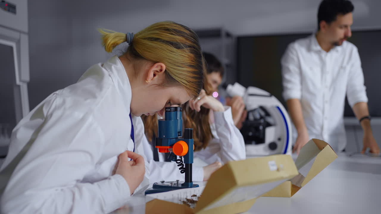 студенты работают в научной лаборатории с помощью микроскопа