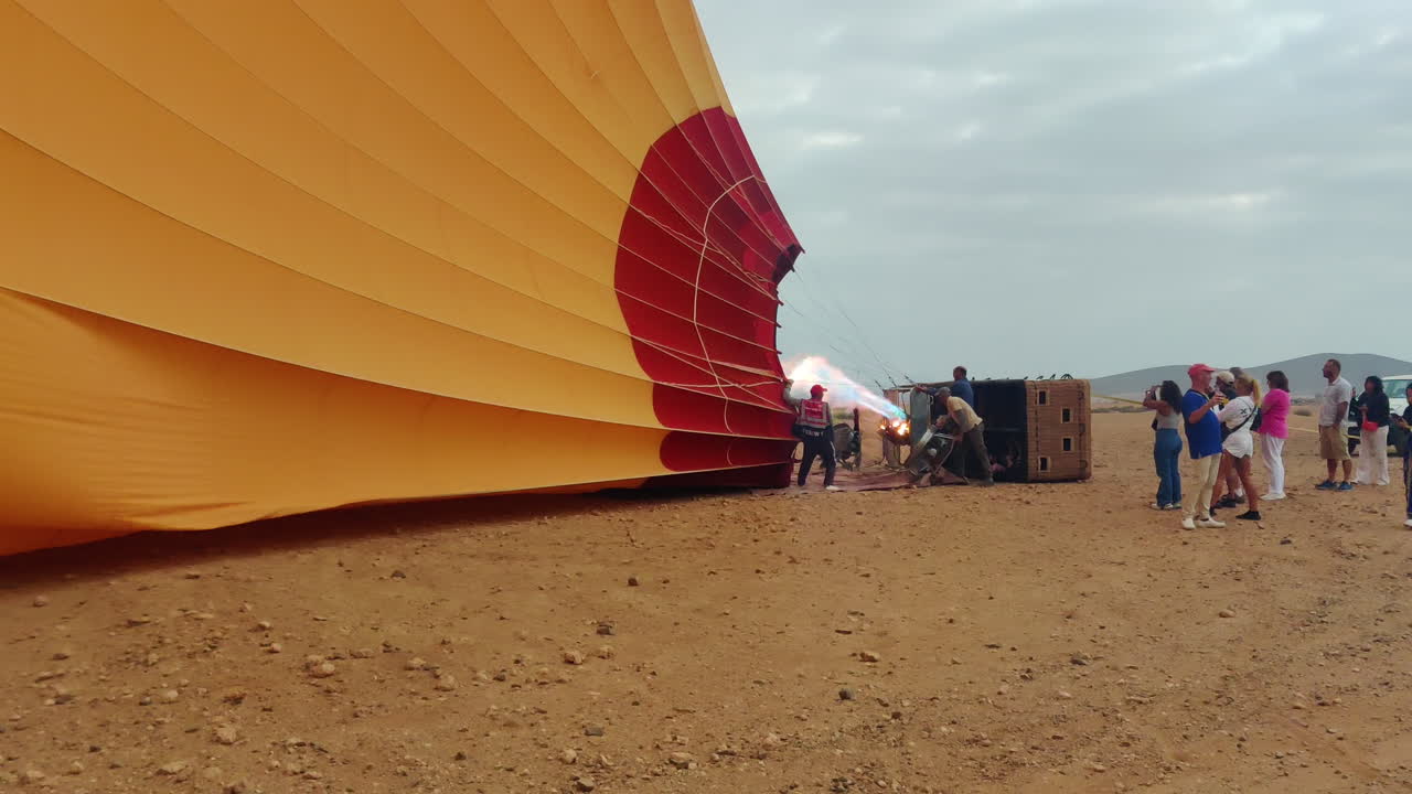 People gather around a hot air balloon being inflated in the Moroccan desert