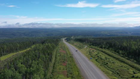 drone flies over alaska highway in british columbia boreal forest