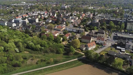 Vista-Aérea-Estática-Del-Barrio-Suburbano-De-La-Ciudad-Alemana-De-Nrw,-El-Tráfico-Por-Carretera-Y-El-Parque-Verde-Bajo-El-Sol-De-Verano