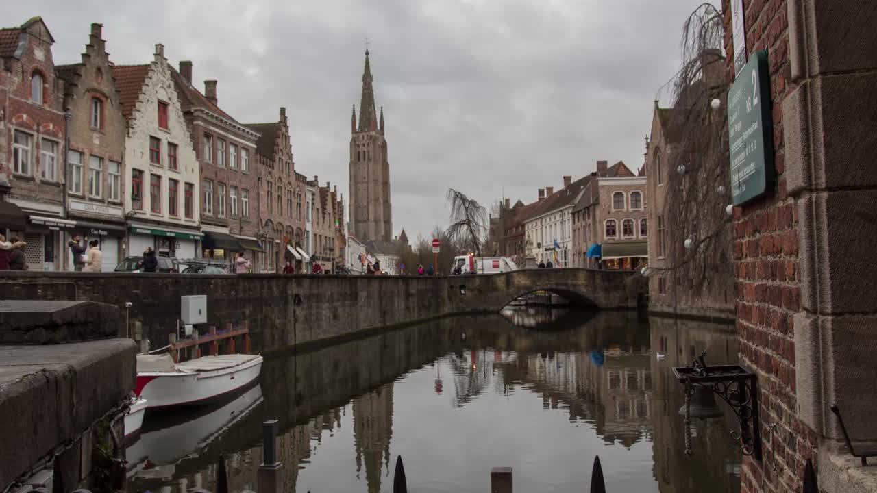 time lapse of the Simon Steven square in the city of Bruges. statue on a square in the city centre. City view with the tower of the Church of Our Lady. Brugge. quay withe people - traffic moving.