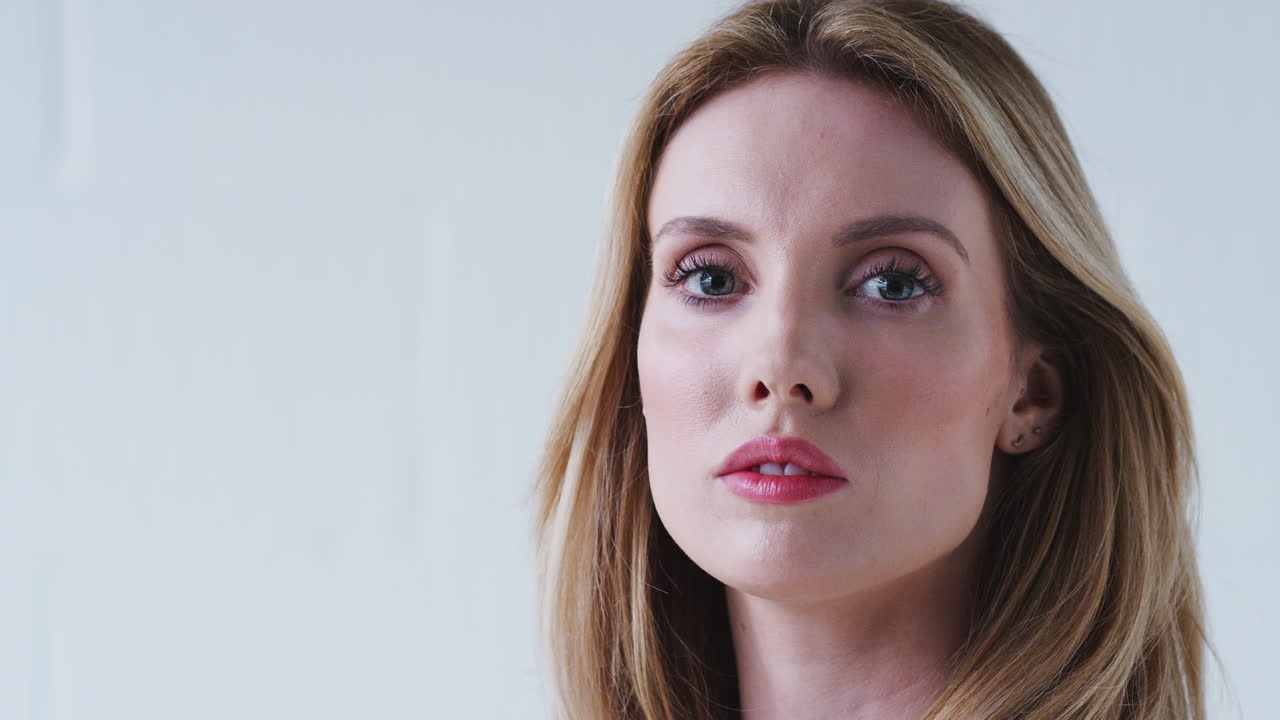 retrato de moda de una joven decidida de pie contra la pared del estudio blanco