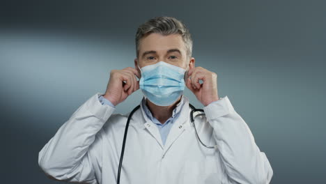 Happy-Good-Looking-Man-Surgeon-Taking-Off-Blue-Mask-Of-His-Mouth-And-Smiling-Cheerfully