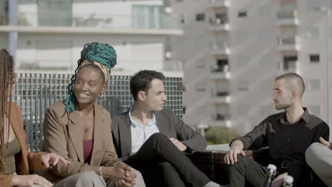 slider shot of coworkers sitting and talking in rooftop cafe