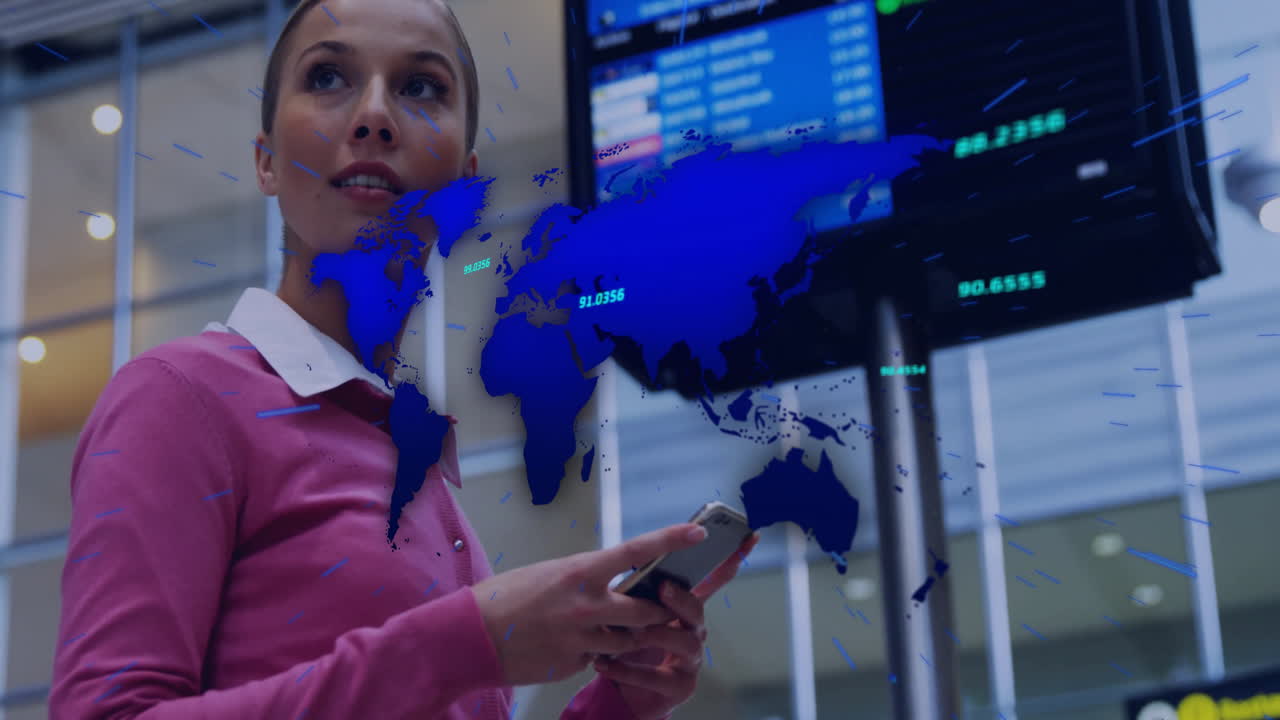 Woman holding smartphone inside transportation hub, viewing world map overlay with data streams