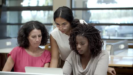 mujeres alegres hablando mientras miran una laptop
