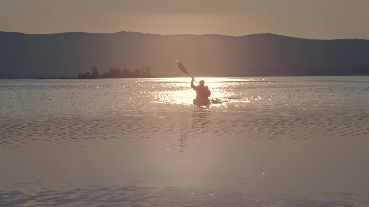 Uomo che rema in canoa sul lago al tramonto