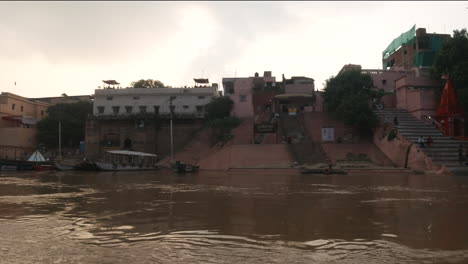 Cinematic-sunset-stunning-beautiful-scenic-Ancient-Holy-city-Varanasi-India-Ganges-River-canal-boat-cruise-Northern-State-people-at-Ghat-Pradesh-Province-landscape-gray-cloudy-left-follow-motion