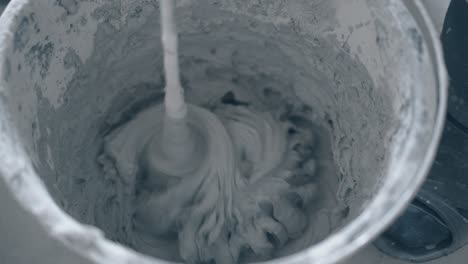 cubo de plástico con masilla gris de mezcla preparada para el manchado