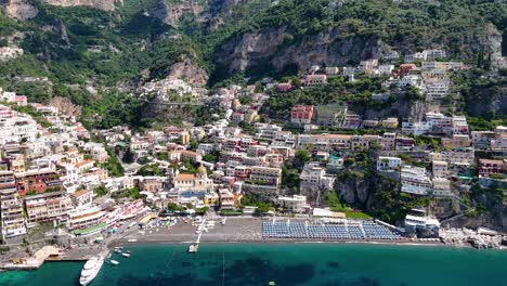 Rotierende-Luftaufnahme-über-Den-Strand-Von-Positano,-Umgeben-Von-Hohen-Berggipfeln-Und-Türkisfarbenem-Wasser,-Amalfiküste,-Italien