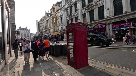 people walking by iconic red phone booth