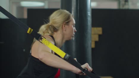 entrenamiento con trx: mujer joven en el gimnasio haciendo entrenamiento de fitness con equipos de bucle de correas de entrenamiento.