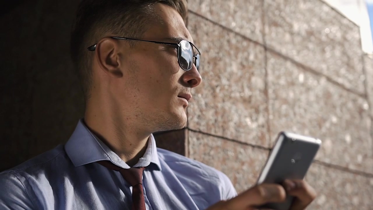 Mand med solbriller bruger smartphone