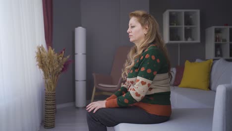 грустная, подавленная зрелая женщина, живущая дома одна, думающая об одиночестве или скорби.