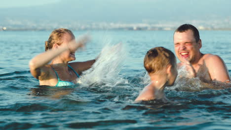 Familia-Feliz-Divirtiéndose-En-El-Agua-De-Mar