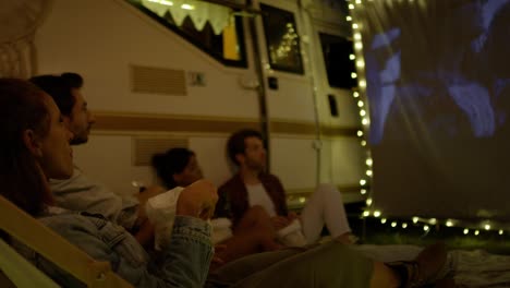 grupo de jóvenes alegres viendo una película en el campamento en la pantalla de proyección