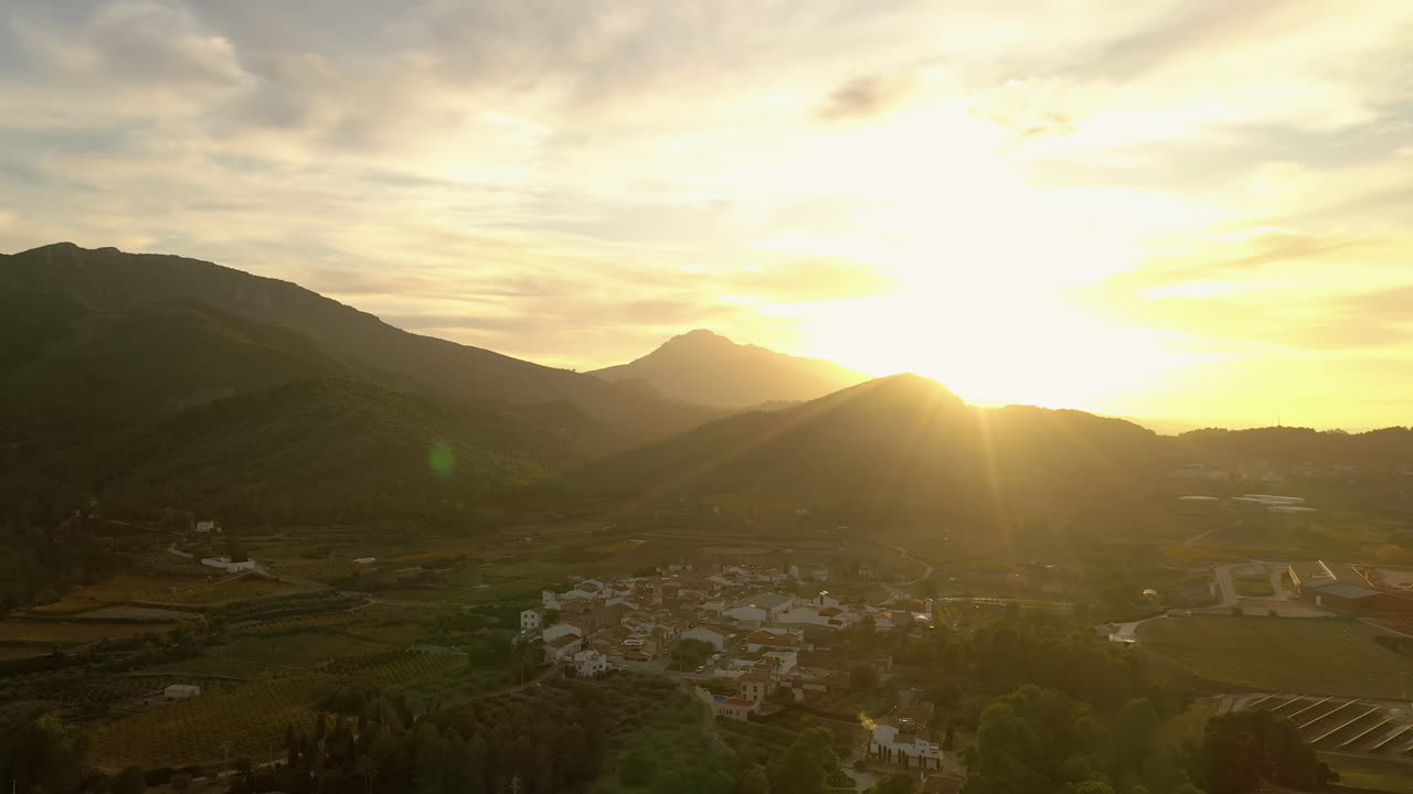 Golden sunset over a charming Spanish village nestled by the mountains.