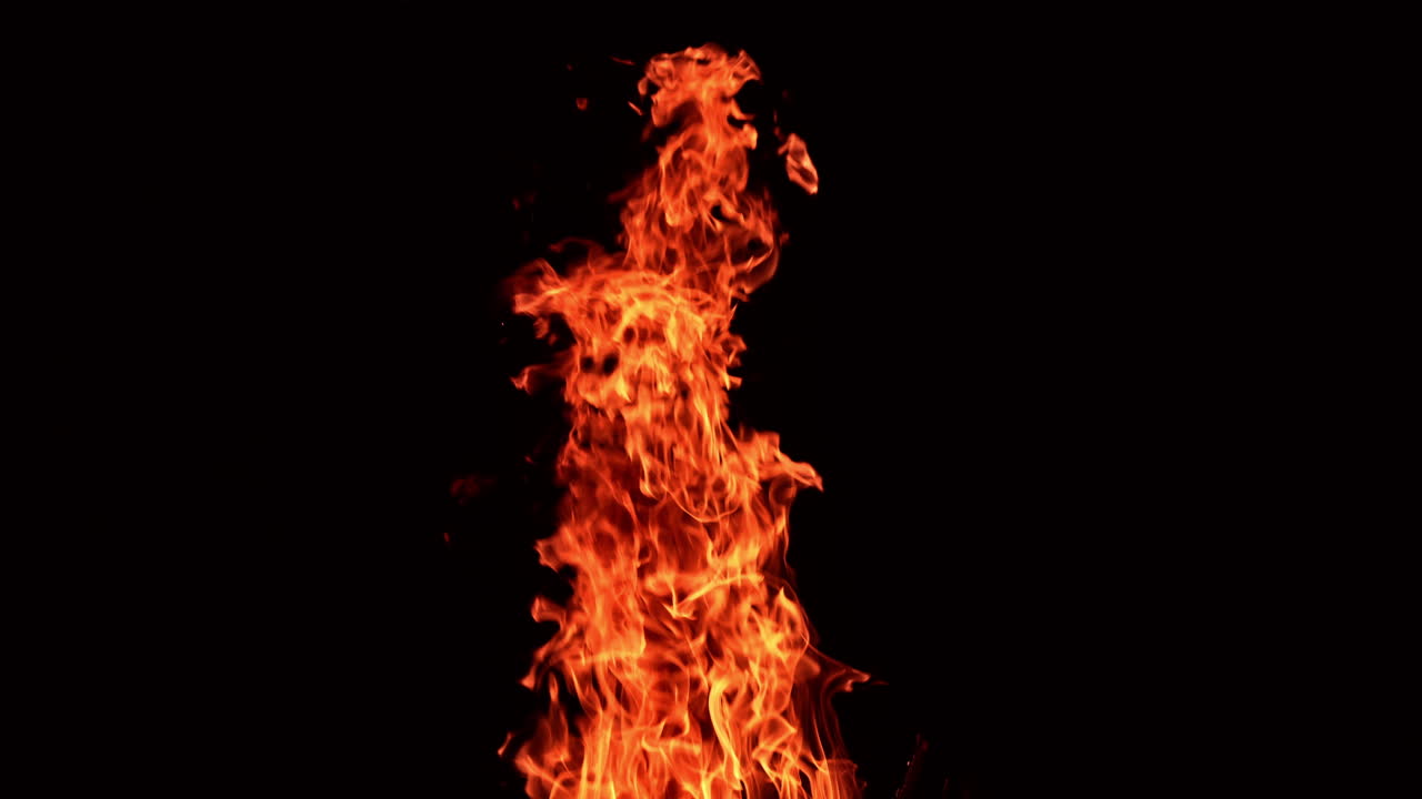Long pillar of red flame going up into the air. Beautiful spots of sparkles flying from the fire. Black backdrop.
