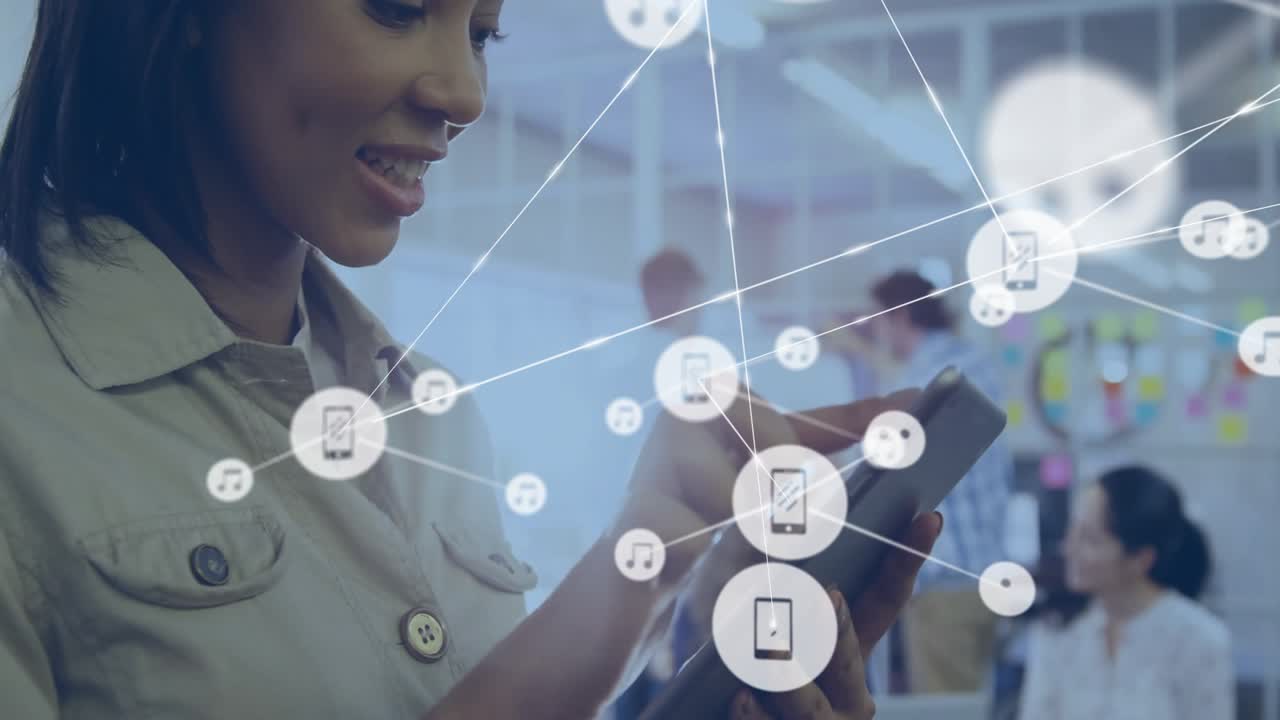 Frau hält Tablet in einem Technologiebüro, während Smartphone- und Musiksymbole nahe einem arbeitenden Team schweben.