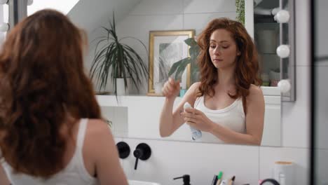 caucasian woman applying spray antiperspirant in the bathroom.