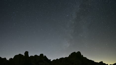 lapso de tiempo de astrofotografía de la vía láctea con la silueta de picos montañosos escarpados en primer plano