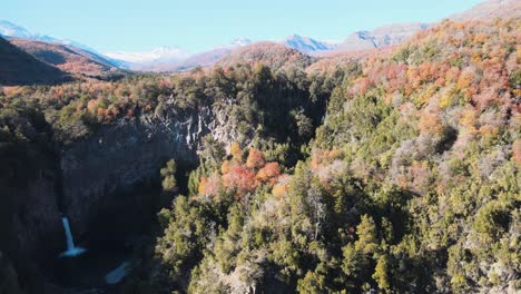 Luftaufnahme-Einer-Kaskade-Und-Vegetation-Mit-Herbstfarben-Mit-Bergen-Als-Hintergrund