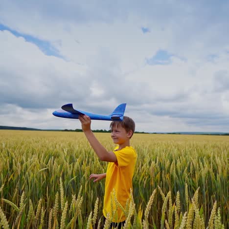 happy boy plays outdoors. cute child holds toy play and turns around joyfully. kid on yellow field playing alone.