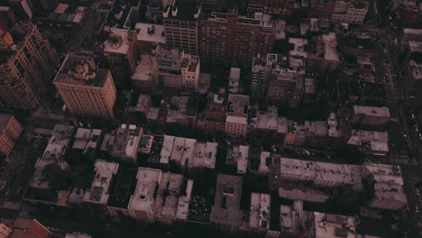 AERIAL:-Tilting-up-from-Skyscraper-Rooftops-to-reveal-Manhattan,-New-York-City-Cityscape--at-Dawn-after-Sunset