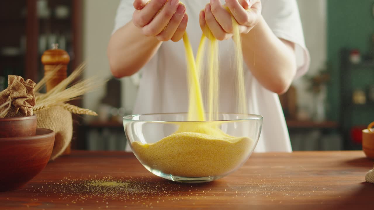 Hands handling cornmeal in a kitchen bowl