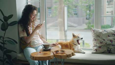 woman with curly hair using smartphone in a cafe with shiba inu