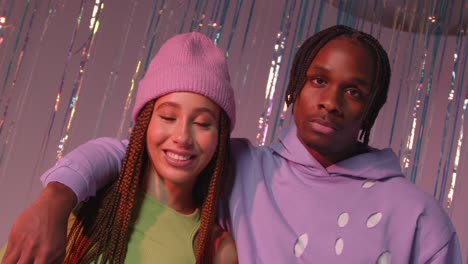 Studio-Portrait-Shot-Of-Young-Gen-Z-Couple-Standing-In-Front-Of-Tinsel-Curtain-Against-Pink-Background-1